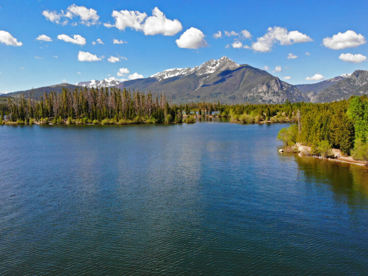 large lake with mountains and trees on partly cloudy day