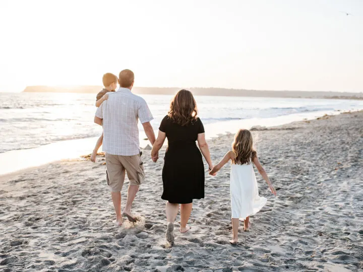 family on the beach gray sand woman man and two kids