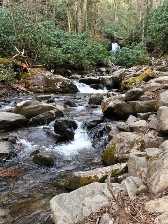 Grotto Falls from a distance with rushing water river rock and green shrubs