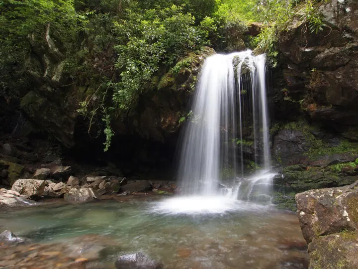 Grotto Falls Smoky Mountains beautiful waterfall flowing into pond below with rocks and greenery surrounding it