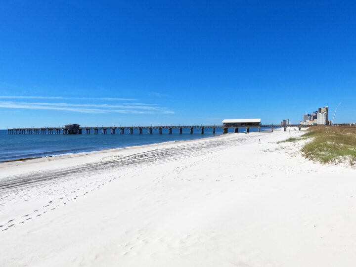 Gulf State Park beach with white sand blue water and pier in distance