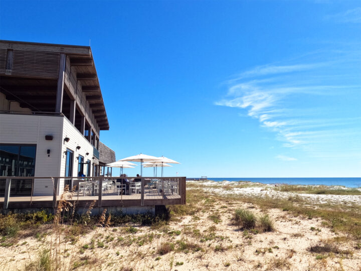 modern restaurant with deck over sand dunes and ocean in distance