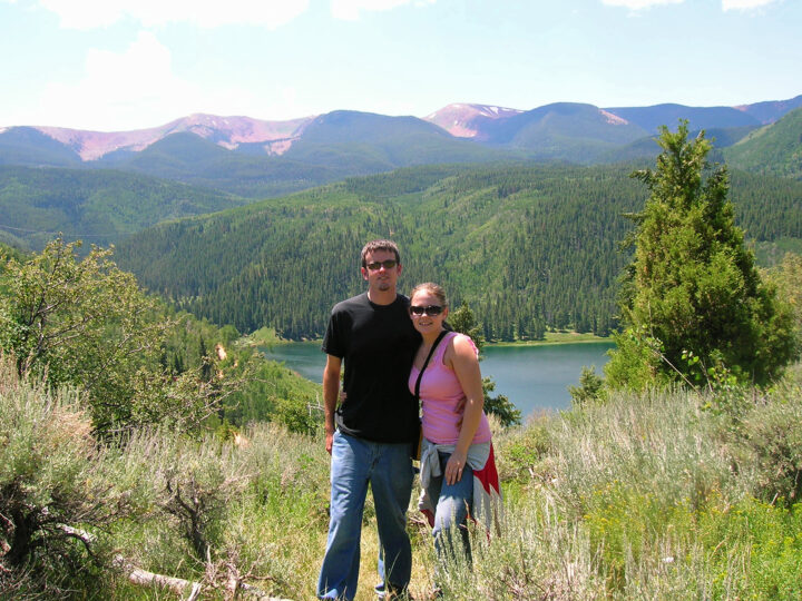 man and woman standing at mountain scene with lake in background