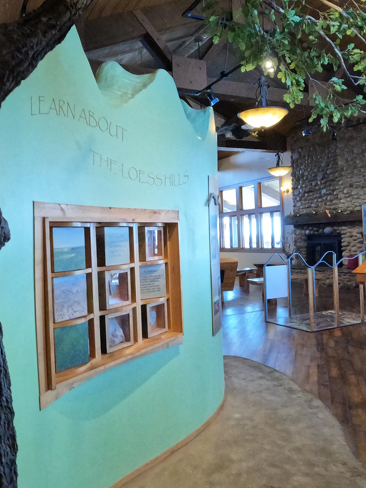 indoor interactive wall that says learn about the loess hills with fake tree and fireplace in distance