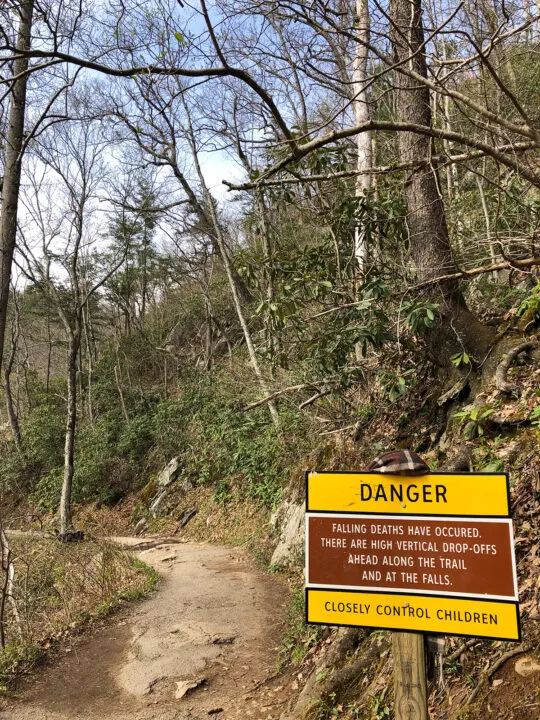 danger sign along trail that reads falling deaths have occurred there are high vertical drop offs ahead along the trail and at the falls closely control children