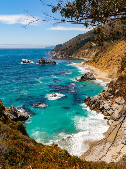 teal water in coastal cove with rocks cliffs and trees