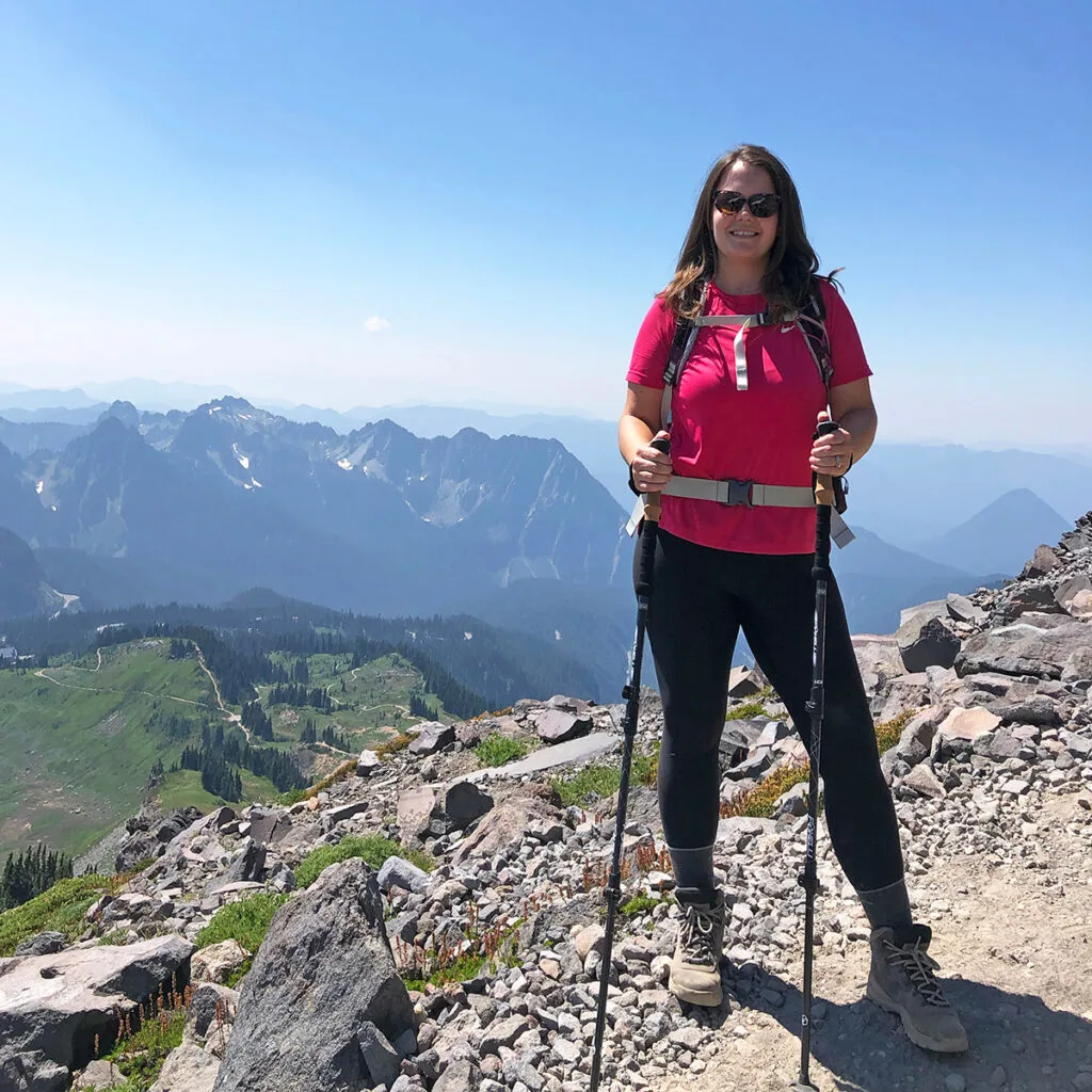 Nikki of inspired routes standing on mountain top with mountains in distance