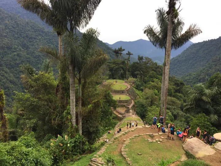 bucket list travel adventures looking over lost city with palm trees mountains and stones with people in distance