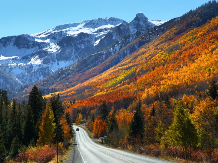 view of the million dollar highway mountainside with snow and orange red yellow fall foliage with road