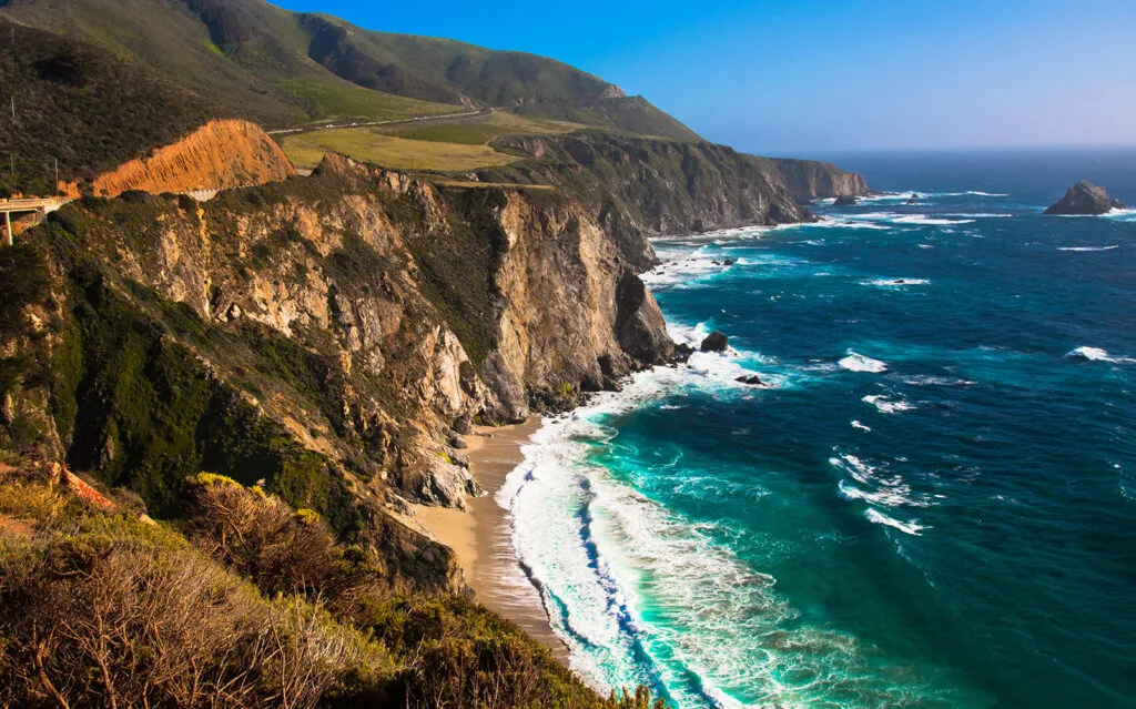 california coast with rocky cliff white waves and road