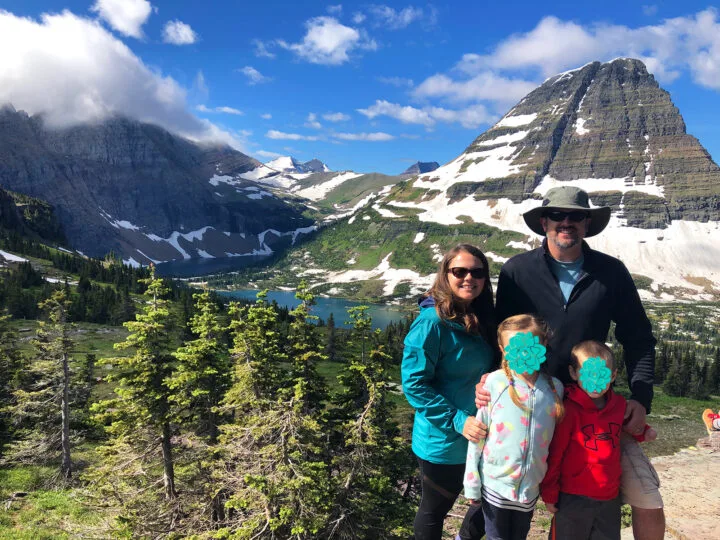 family standing at mountain scene with blue sky lake and trees in background