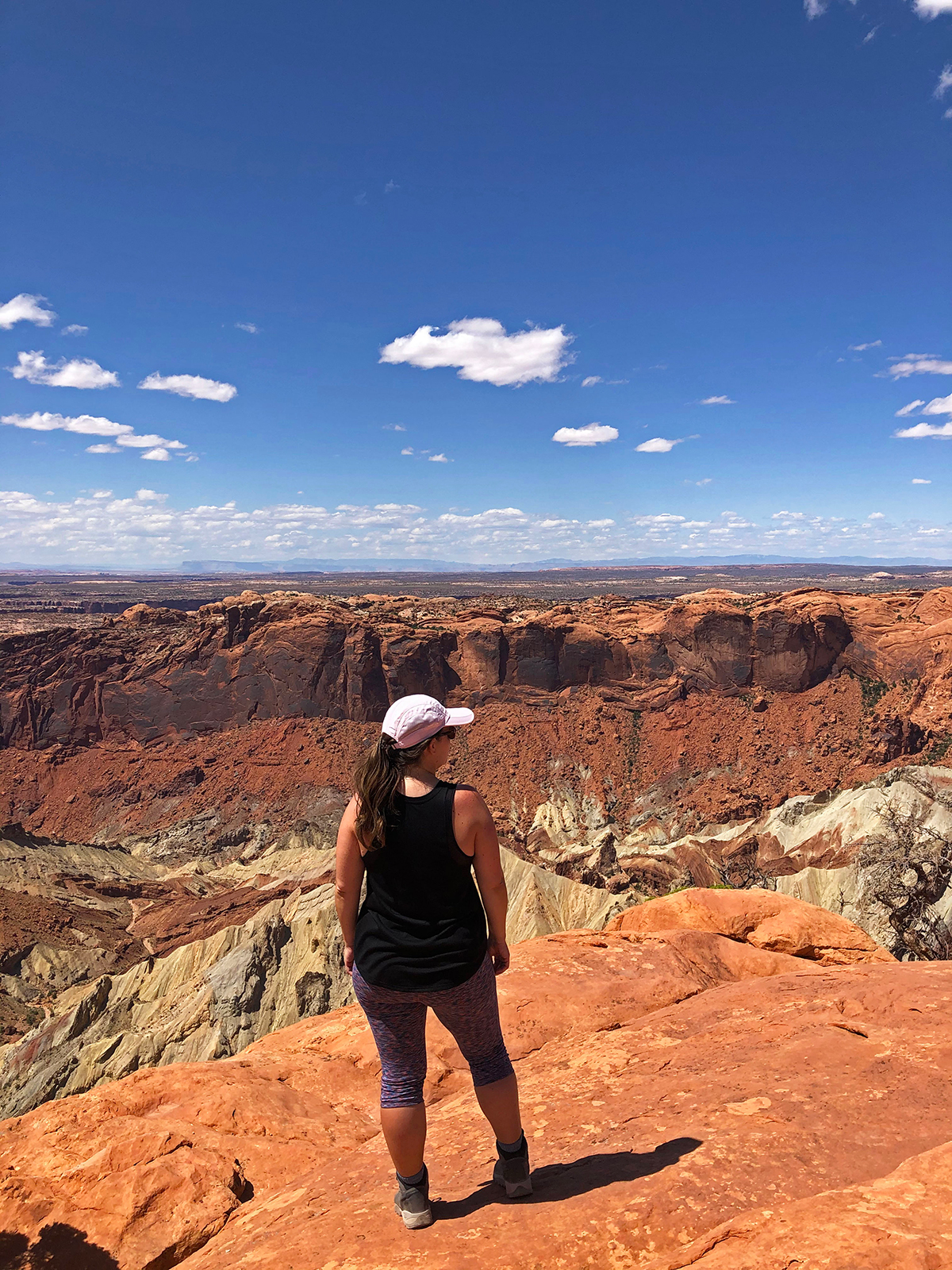woman standing at canyon with multicolored rocks and blue sky