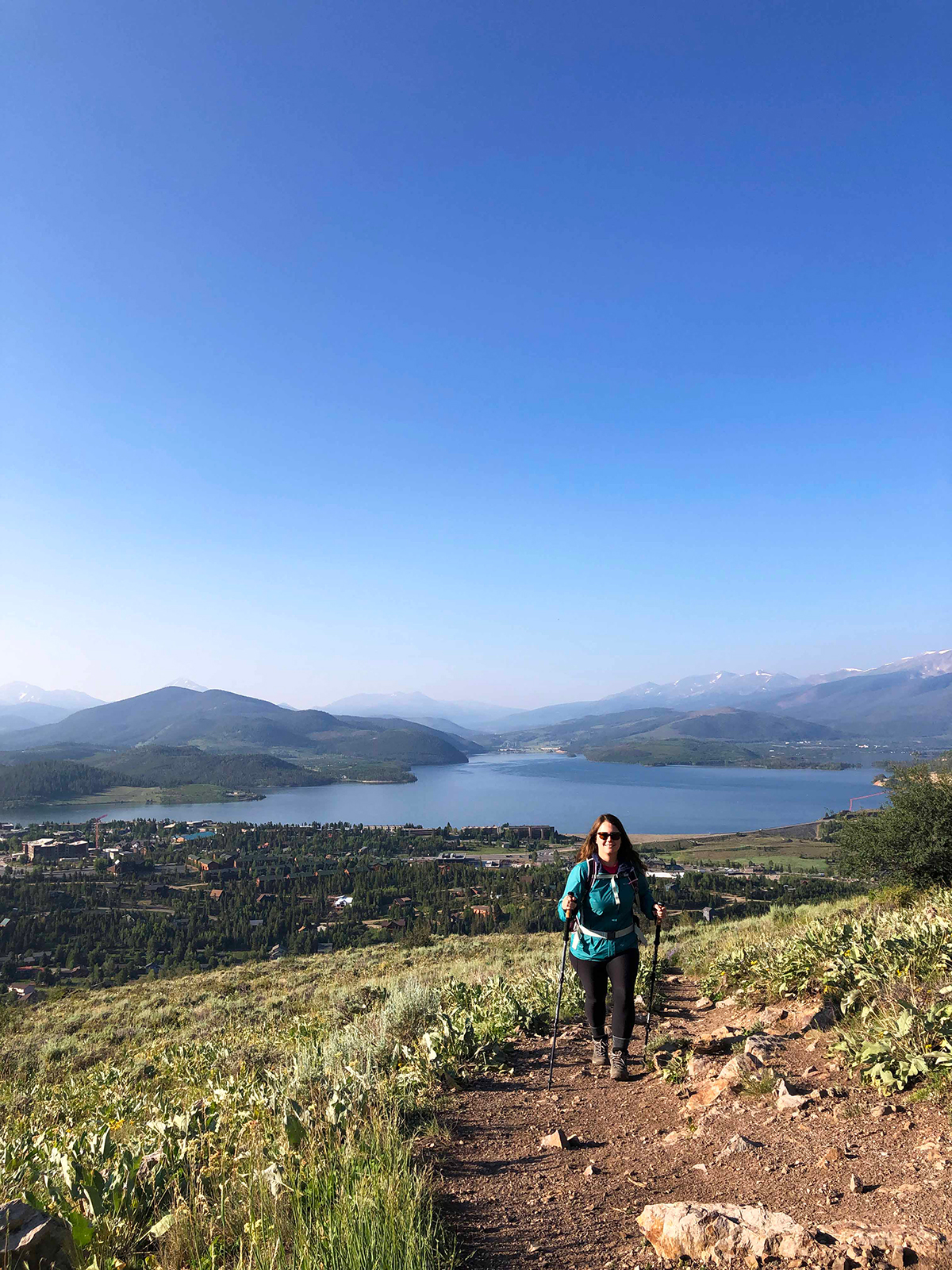 woman on hiking trail in Colorado with lake and mountains in background