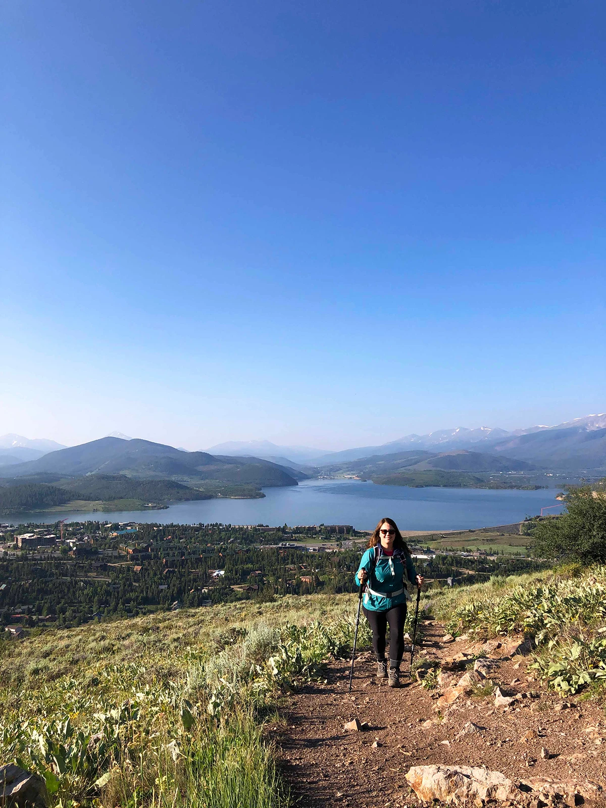 woman on hiking trail in Colorado with lake and mountains in background