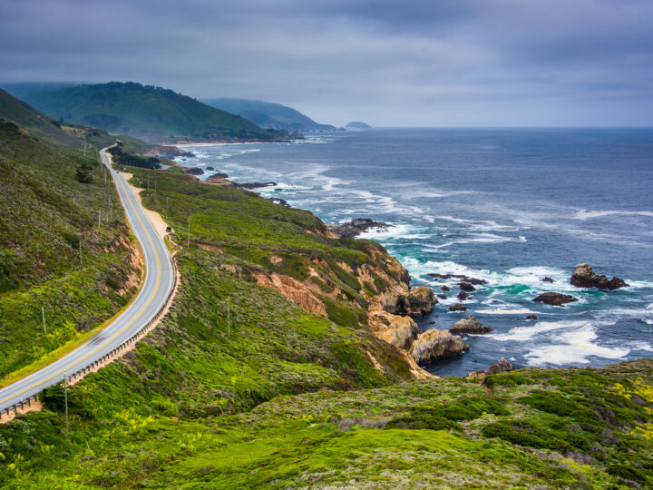 california coast road trip view of water mountains and road on cloudy day