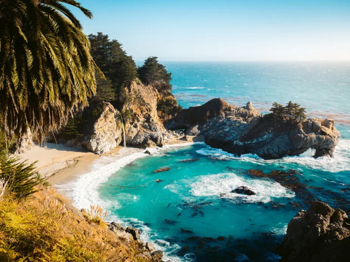 california coast view of teal ocean rocks waterfall in distance