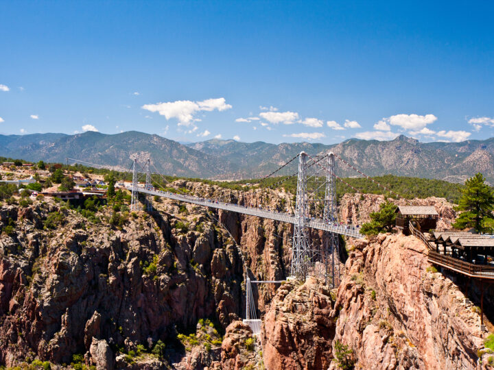 best drives in colorado view of suspension bridge over gorge with mountains in distance