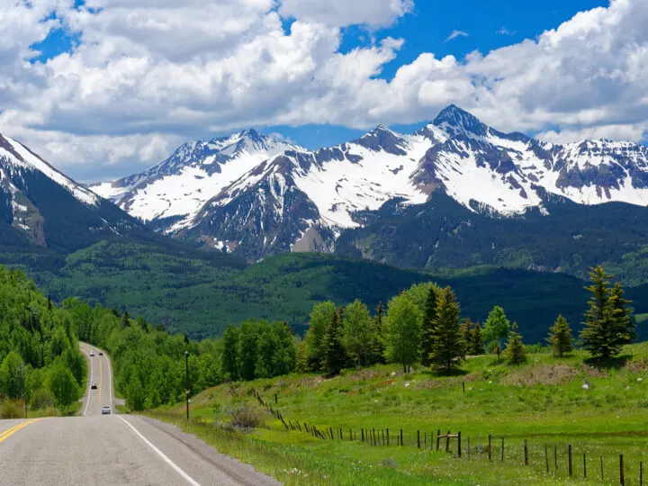 scenic drives Colorado view of road with trees and mountains with snow up ahead