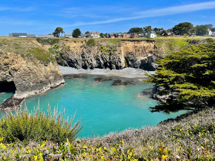 best places to travel in the US in September Mendocino CA teal colored lake with greenery surrounding and houses in distance