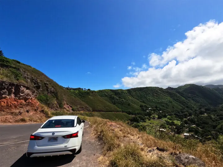 white car with road and mountain ridge in distance