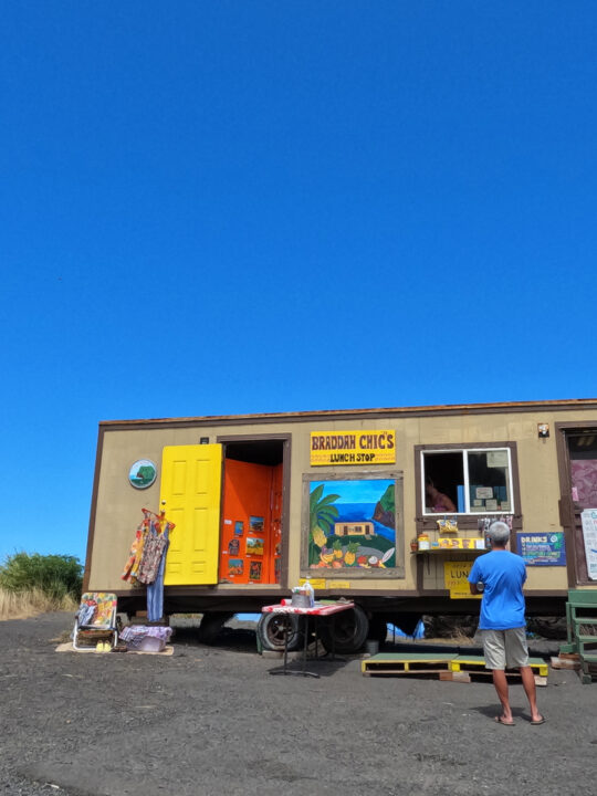 braddah chics lunch stop food trailer with man standing out front and blue sky