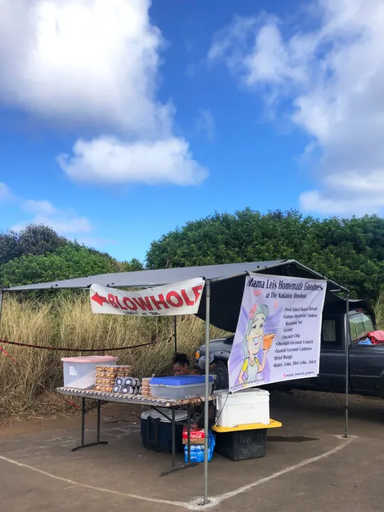 food stand with signs and trees on partly cloudy day