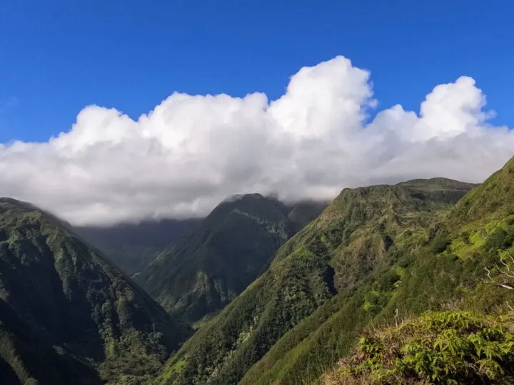 waihee ridge trail Maui with lush greenery mountains valley white clouds on blue sky day