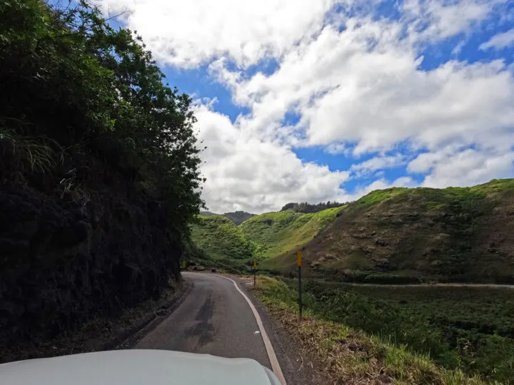 narrow road kahekili highway with car hood valley and hills on cloudy day