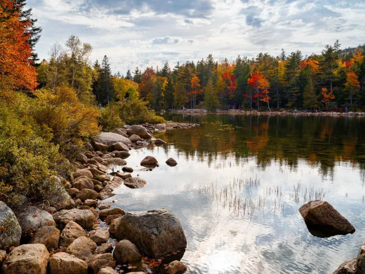 best national parks to visit in October view of lake with rocky shore fall foliage on surrounding trees