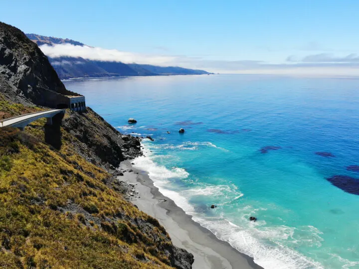 Big Sur california view of grey beach teal water scenic road through mountain
