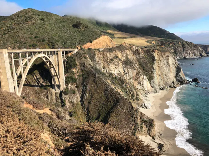 view of Big Sur bridge with cliff to ocean and arched bridge