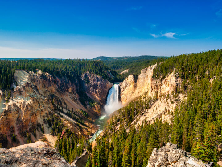 lower falls Yellowstone large canyon waterfall with trees yellow rocks blue sky