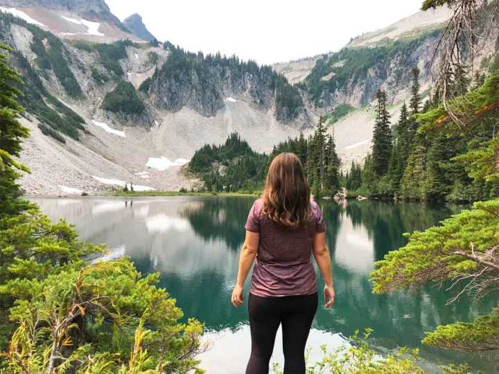 bench and snow lake trail in paradise mt rainier woman standing at alpine lake with trees and mountain in distance