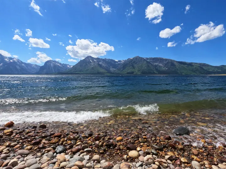 view of Jackson lake grand teton rocky shore waves and mountains in distance