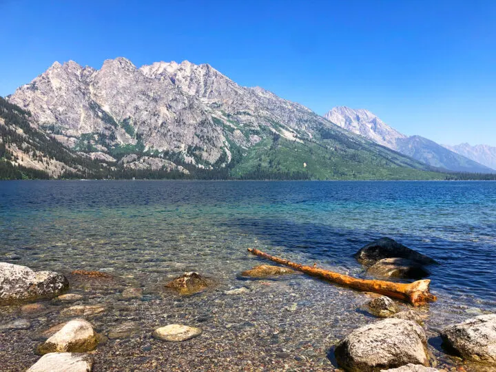 Inspiration point Jenny lake view of rocky shore blue lake water with mountain in distance