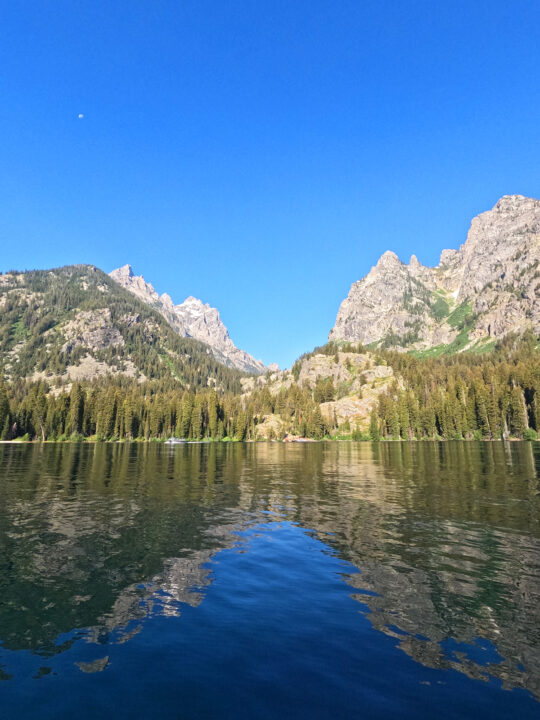 view from lake Jenny of inspiration point grand teton tall mountains reflecting on water