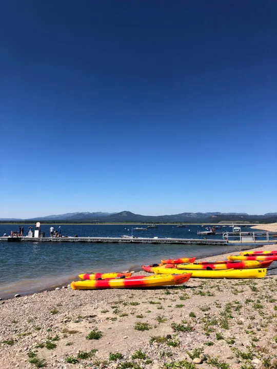 things to do in grand teton rent kayaks sitting on shore along lake