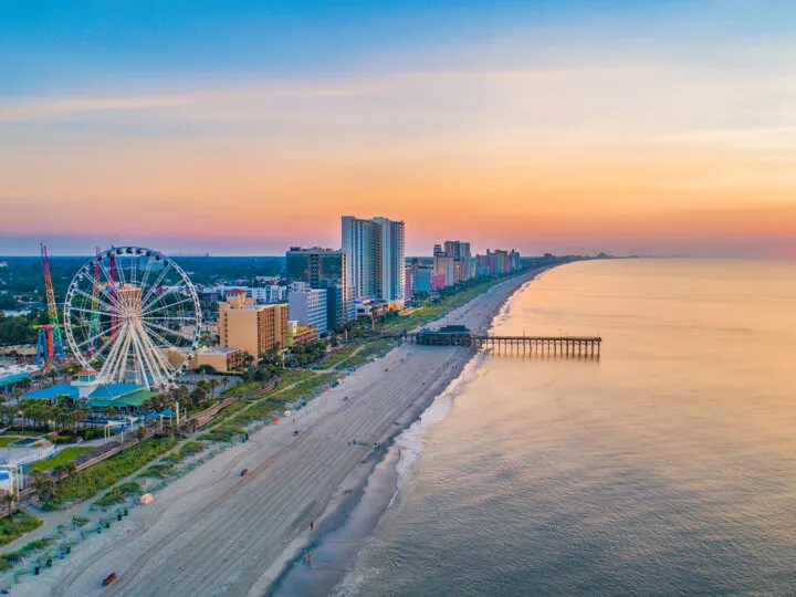 warm places to visit in December in USA view of beach from above at sunset with city skyline bridge and ferris wheel
