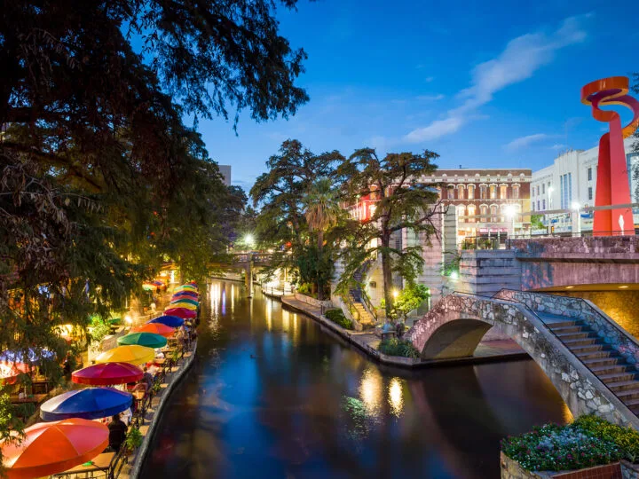 river at dusk with restaurant brick sidewalk and trees