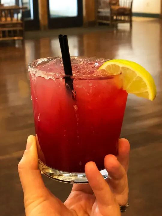 womans hand holding huckleberry margarita