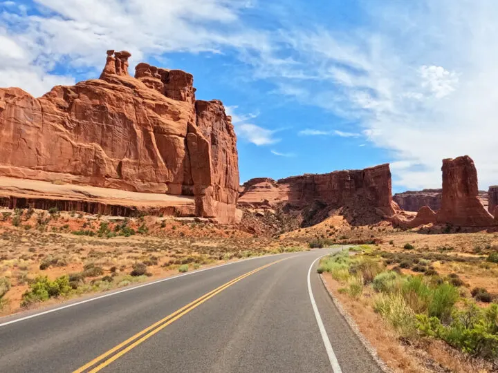 Utah national parks road trip view of road with red rocky spires in distance