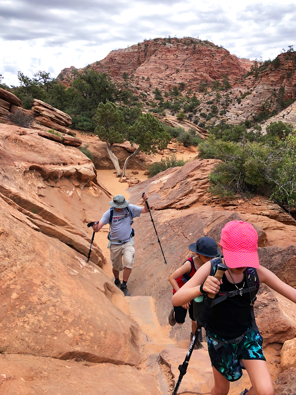 kids and man hiking up rocky terrain