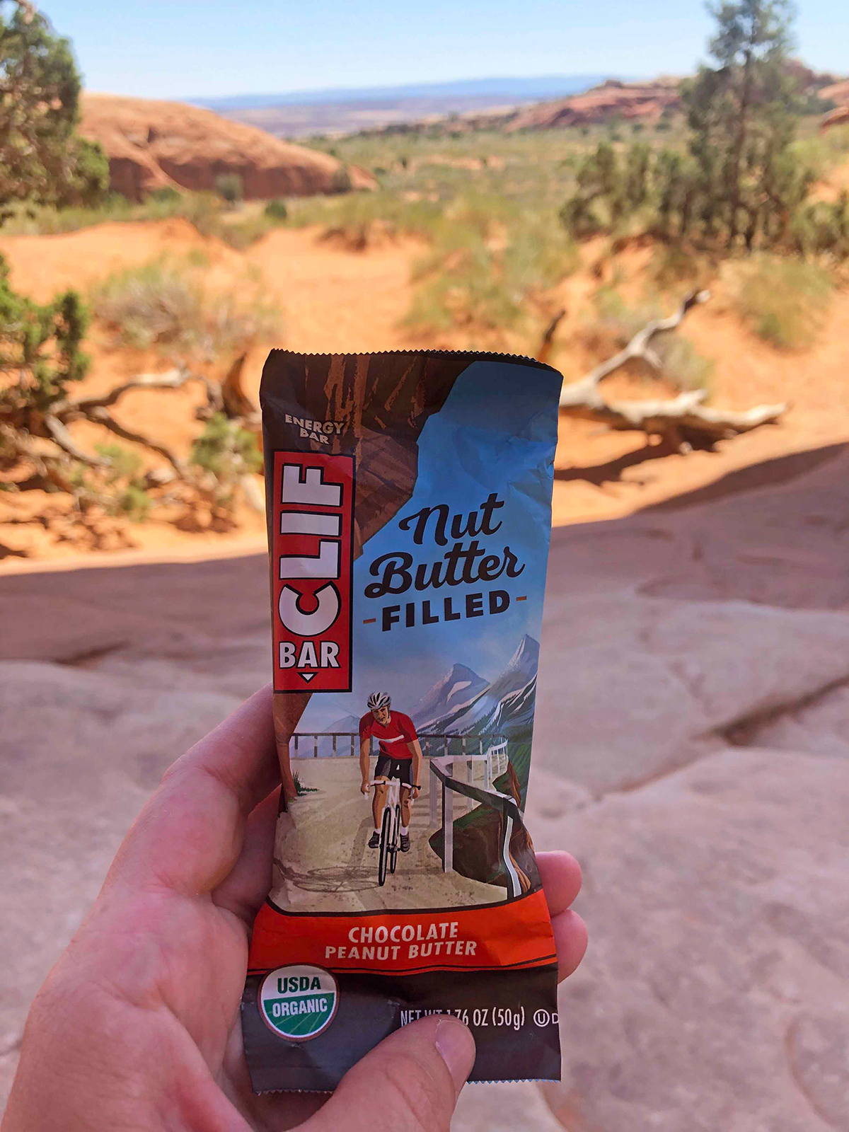 photo of cliff bar nut butter filled with hand holding bar with desert in background