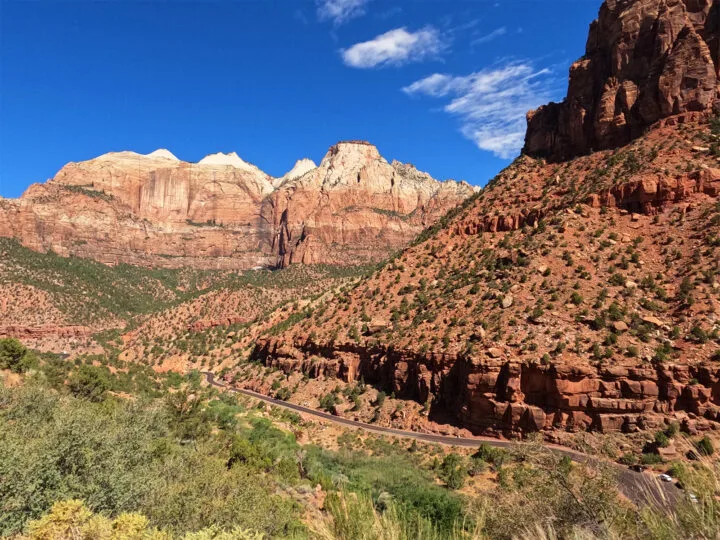 road winding through red rocky cliffs on a Utah national parks road trip