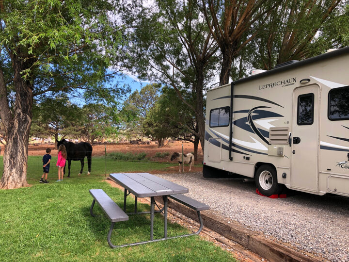 rv parking space at campground surrounded by nature with tan rv near Torrey UT