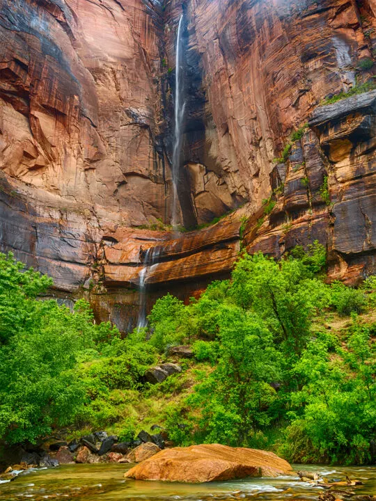 waterfall down rock to pool with trees below