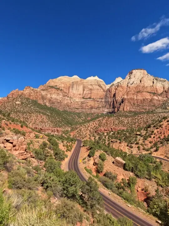 road through valley and cliffs on sunny day