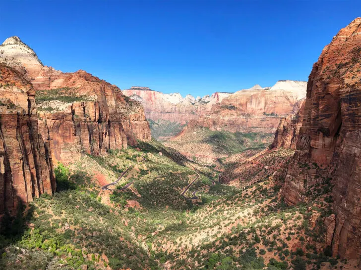 Zion National park view of canyon with massive orange rocky cliffs and road deep in valley