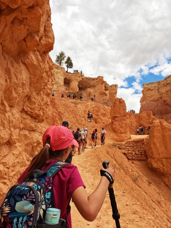 young kid hiking Wall Street Bryce canyon carrying hiking poles and backpack orange rocks surrounding