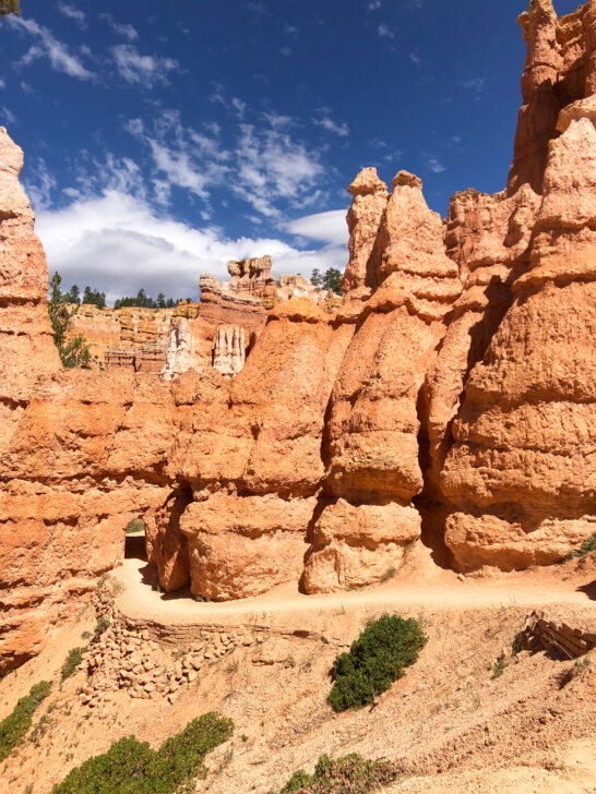 hiking Queen's garden trail Bryce Canyon national park view of trail through orange rocky spires blue sky in distance